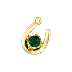 Macro shot of horseshoe pendant with gold plating and a faceted green gemstone