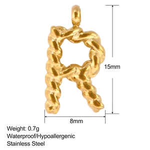 Makroansicht des goldenen R-Buchstabenanhängers aus Edelstahl mit gedrehter Textur