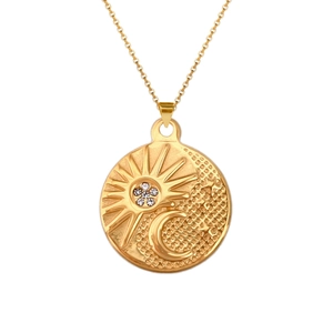 Close-up of golden coin pendant featuring celestial sun and moon relief with tiny rhinestones