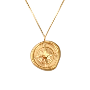 Macro detail of gold vintage compass star pendant necklace on a refined link chain