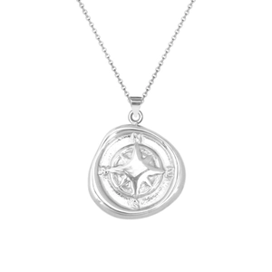 Macro detail of silver compass pendant with NESW engravings and celestial wax seal design