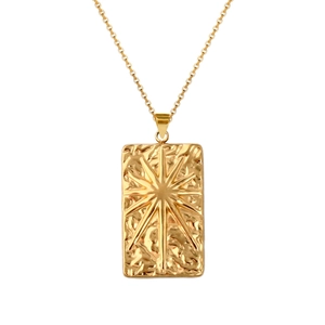 Detail of gold rectangular pendant with hammered texture and embossed sun star pattern