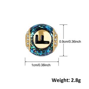 Dettaglio charm lettera F con paillettes verdi e intarsio di zirconi cubici