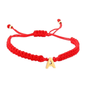 Detalle de pulsera trenzada roja con dije de letra A dorada y nudo ajustable corredizo