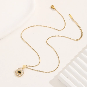Collana in acciaio dorato con pendente a quadrifoglio nero e raggiera in zirconi bianchi
