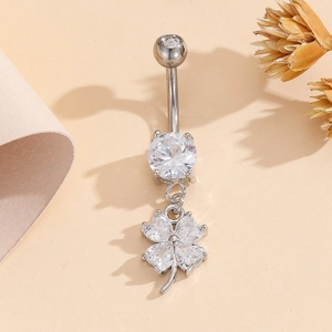 Bauchnabelpiercing aus Edelstahl mit Kleeblatt-Zirkonia-Anhänger auf warmem Hintergrund