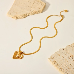 Dettaglio del ciondolo a cuore in oro 18K su catena a serpente sottile su pietre naturali