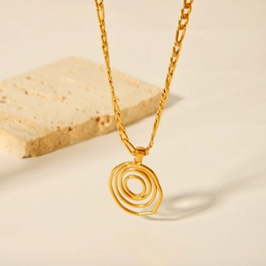 Dettaglio del ciondolo a spirale in oro su una catena a maglie piatte su base in pietra