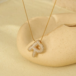 Detail of 18K gold plated letter R pendant with cubic zirconia on a snake chain