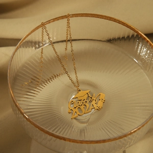 Detail van de 2024 afstudeerhoed ketting met 18K goudlaag op luxe stoffen decor