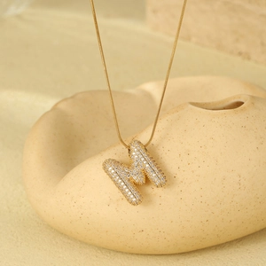 Detailed view of gold-plated letter M pendant with zircon inlay on a snake chain necklace
