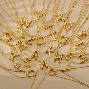 Minimalist gold bubble alphabet necklaces A-Z with smooth snake chains on white fabric
