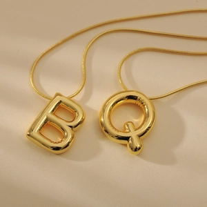 Macro detail of golden balloon letter pendants B and Q on elegant snake chains