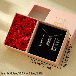 Parure bijoux dorée avec pendentif goutte et boucles dans un coffret de roses