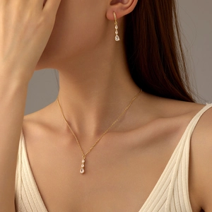 Vue détaillée d'une parure collier et boucles d'oreilles dorée avec zircons en goutte