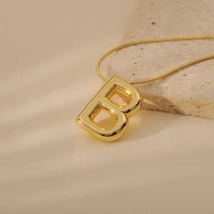 Macro shot of gold bubble letter B pendant necklace with elegant snake chain detail