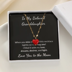 Detail of red heart pendant necklace on a message card inside a white jewelry gift box