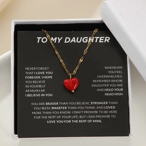 Golden necklace with red heart pendant on inspirational message card in gift box