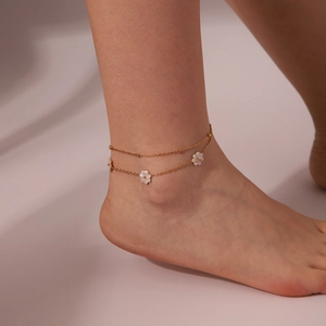 Detalle de la tobillera de doble capa bañada en oro 18K con colgante de margarita blanca