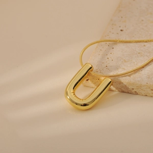 Detailed view of a polished golden U-shaped bubble letter pendant on a sleek snake chain