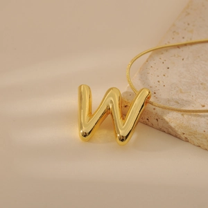 Detailed view of chunky golden letter W pendant on a sleek snake chain necklace