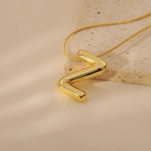 Detailed close-up of bubble-style gold letter Z pendant on a sleek snake chain necklace