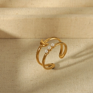 Macro detail of 18K gold star moon ring featuring white pearls on beige textured background