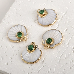 Detailed view of four fan-shaped shell pendants with gold plating and green stone inlays