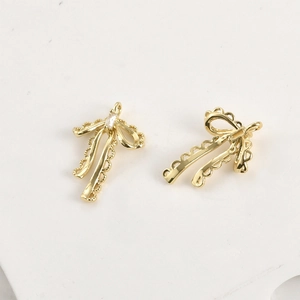 Macro view of 14k gold plated bow pendant with lace edges and zircon inlay detail