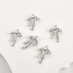 Macro detail of five silver bow pendants with lace edges and central baguette zircon stones