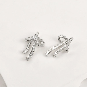Detailed view of silver bow pendant with rectangular zircon and lace edge design