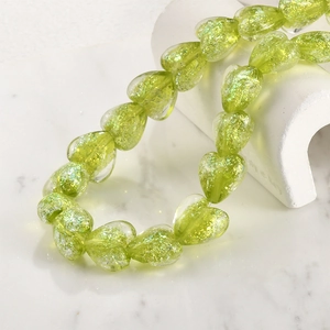 Macro detail of lime green iridescent heart-shaped glass beads for DIY jewelry making