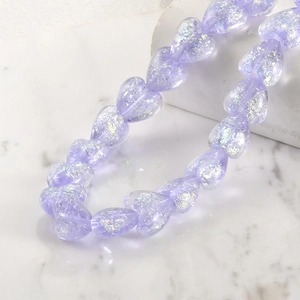 Macro shot of translucent purple heart-shaped beads with aurora glitter for DIY jewelry