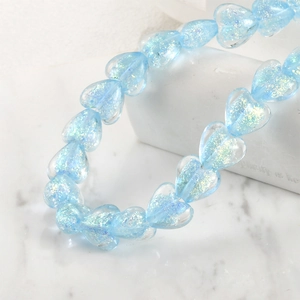Macro shot of light blue heart-shaped iridescent glass beads for DIY jewelry