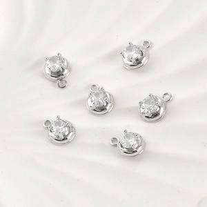 Macro detail of six silver-plated round pendants with clear cubic zirconia in 4-prong settings