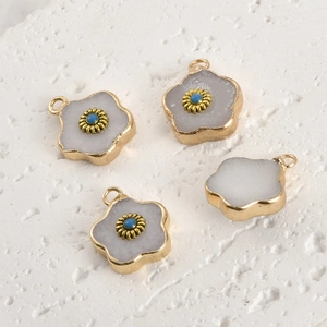 Close-up of four floral gemstone pendants with gold edges and blue bead centers