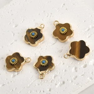 Detailed view of flower-shaped pendants with tiger eye stone and gold-plated frames