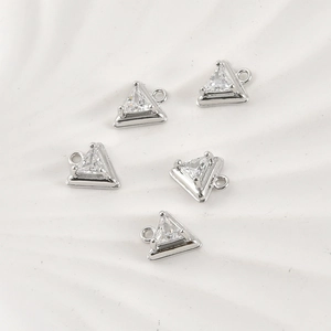 Close-up of five silver-plated triangle charms with clear zircons for jewelry making