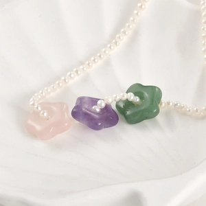 White seed bead necklace with pink, purple, and green crystal flower charms on shell tray