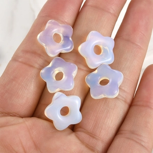 Macro shot of five-pointed star natural crystal opal beads held in a palm for size reference