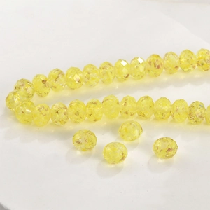 Detalle macro de cuentas de vidrio facetadas amarillo limón con pan de oro para joyas DIY