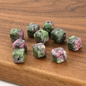 Macro detail of cube-shaped natural anyolite stone spacer beads on a wooden tray