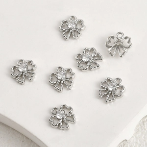Detailed view of silver bow-shaped hollow pendants with zircon for DIY jewelry making
