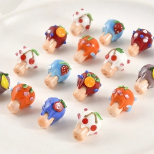 Macro view of handmade glass beads featuring colorful fruit and dessert glaze patterns