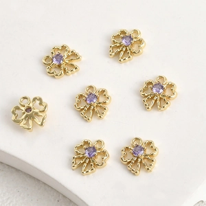 Macro detail of seven gold plated hollow floral pendants with central purple zircons