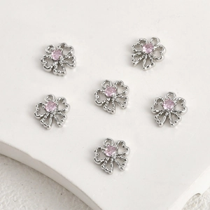 Detailed view of six silver bow pendants with pink zircon stones for DIY jewelry making
