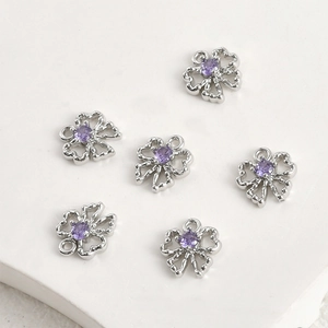 Detailed view of silver hollowed four-leaf clover charms with purple zircon inlay