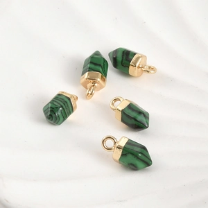 Gros plan de cinq pendentifs hexagonaux en malachite avec attaches dorées en boucle