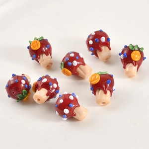 Macro shot of handmade red mushroom glass beads with colorful dots for DIY jewelry