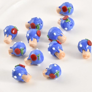 Macro shot of handmade blue glass mushroom beads with white polka dots for jewelry making